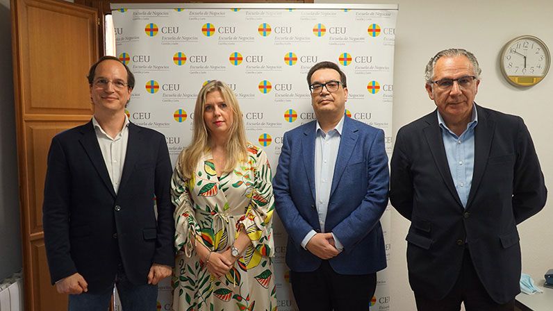Foto de cuatro personas con el fondo del logotipo de escuela de negocios CEU